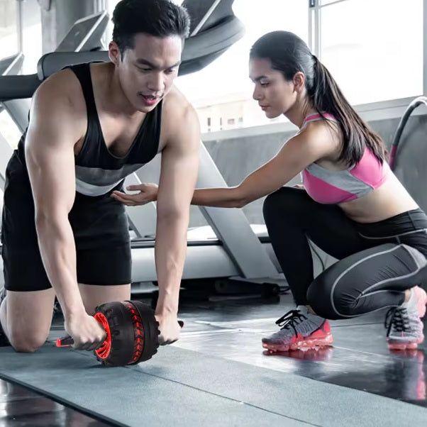 Abdominaux roue deux personnes faisant du renforcement ensemble au gym avec l'outil