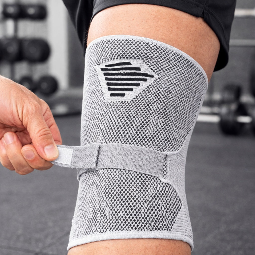 Genouillere pour sport porté par une personne tenant l'attache arrière