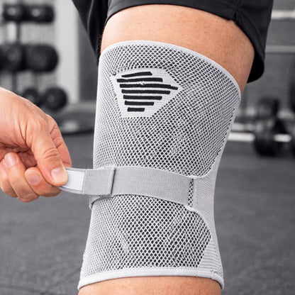 Genouillere pour sport porté par une personne tenant l'attache arrière
