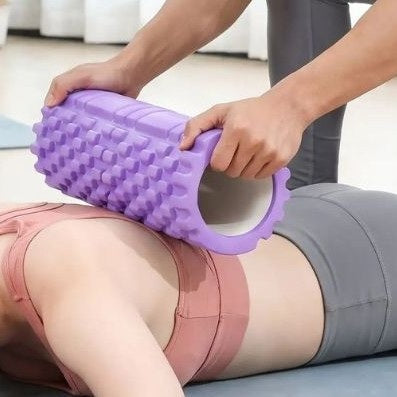 Rouleau de massage modèle de couleur mauve en usage sur un dos d'une personne