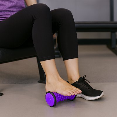 Rouleau de massage pied une personne assis sur un banc d'exercice utilisant l'accessoire