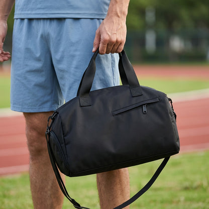Sac de sport montrant une personne en partie et en tenant l'accessoire  par la poignées supérieur dans un terrain de conditionnement physique